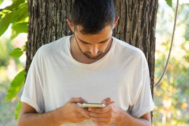 Genç adam dışarıda cep telefonu kullanıyor.