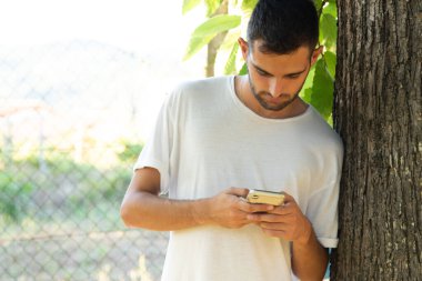 Genç adam dışarıda cep telefonu kullanıyor.