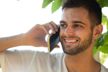 Genç adam dışarıda cep telefonu kullanıyor.