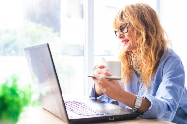 Bilgisayarı ve kahvesi evde ya da internet ofisinde olan iş kadını