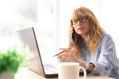 İş kadını bilgisayar ve cep telefonuyla çalışıyor