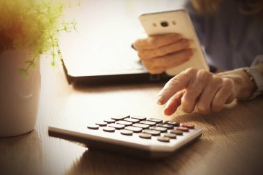 Masasında hesap makinesi ve bilgisayarla iş kadını eli