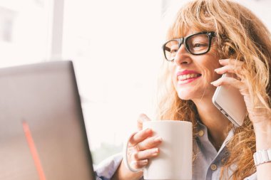 Ofisinde ya da evinde cep telefonu ve bilgisayarı olan iş kadını