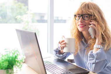 Ofisinde ya da evinde cep telefonu ve bilgisayarı olan iş kadını