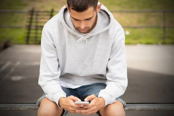 Młody Człowiek Patrząc Telefon Komórkowy Zewnątrz — Zdjęcie stockowe