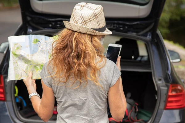 woman traveling by car with map and mobile phone