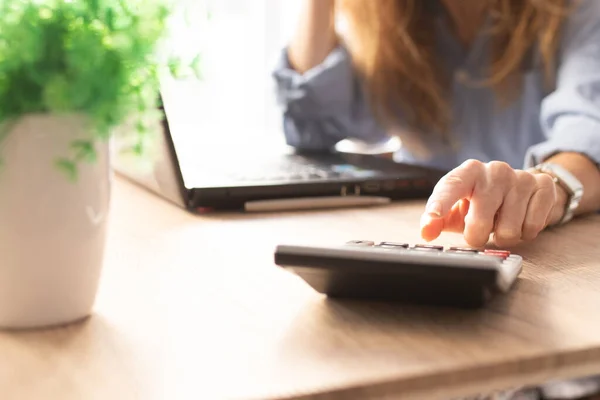 business woman hand with calculator and computer on desk