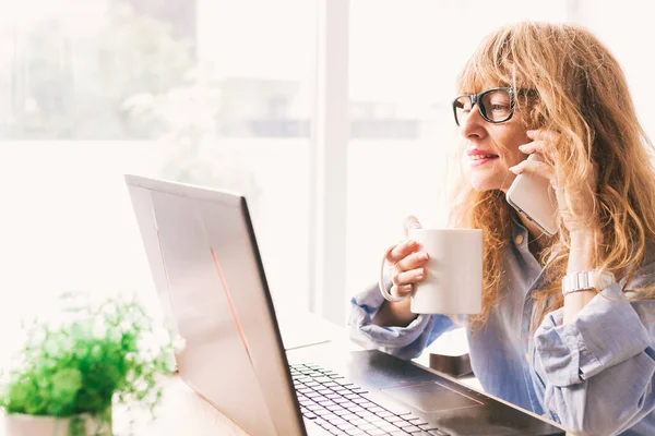 Ofisinde ya da evinde cep telefonu ve bilgisayarı olan iş kadını