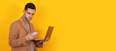 Akıllı telefonu ve dizüstü bilgisayarı olan genç adam arka planda izole edilmiş.