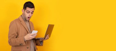 Akıllı telefonu ve dizüstü bilgisayarı olan genç adam arka planda izole edilmiş.