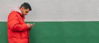 Duvarında cep telefonu olan sıradan bir genç adam.