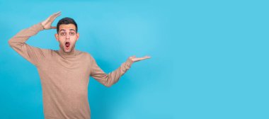 Şaşırmış genç adam arka planda izole edilmiş ve uzayı işaret ediyor.