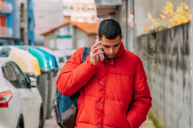 Adam şehirde yürürken telefonla konuşuyor.