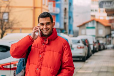 Genç adam sokakta akıllı telefon kullanıyor.