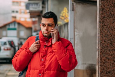 Şehir caddesinde telefonu ve sırt çantası olan genç adam.