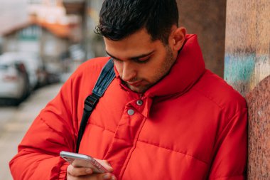 Genç adam sokakta akıllı telefon kullanıyor.