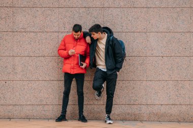 Sokak duvarında cep telefonu olan gençler ya da arkadaşlar