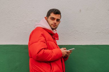 Duvarında cep telefonu olan sıradan bir genç adam.
