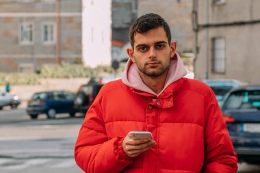 Şehir sokaklarında cep telefonu olan genç bir adam.