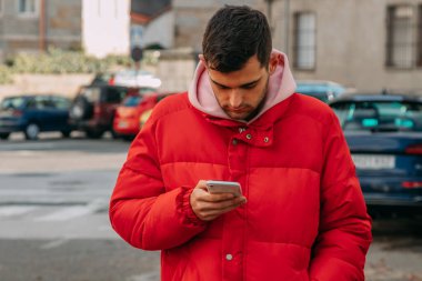 Şehir sokaklarında cep telefonu olan genç bir adam.