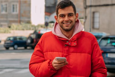 Şehir sokaklarında cep telefonu olan genç bir adam.