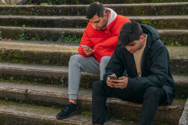 Gençler şehrin merdivenlerinde cep telefonlarıyla eğleniyorlar.