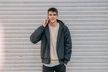 Genç bir adam şehir caddesinde kör bir adamın önünde cep telefonuyla konuşuyor.