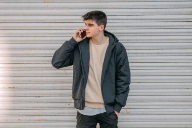 Garaj kapısında cep telefonu olan genç bir adam.