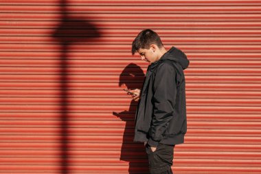 Kırmızı körün önünde cep telefonu olan bir genç.