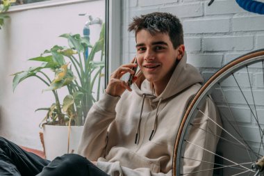 Evde cep telefonu olan genç bir adam.