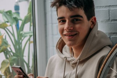 Evde cep telefonu olan genç bir adam.