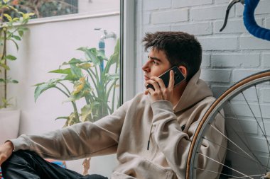 Evde cep telefonu olan genç bir adam.