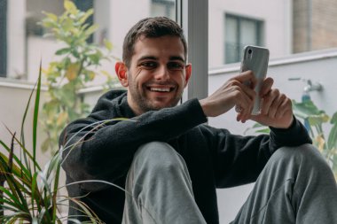 Evde cep telefonu olan genç bir adam.