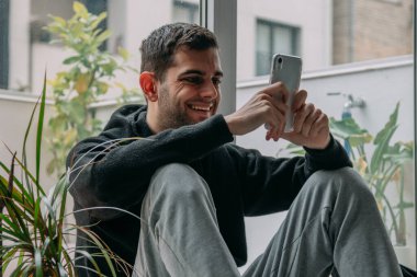 Evde cep telefonu olan genç bir adam.