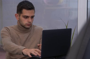 Evde dizüstü bilgisayarla çalışan bir adam.