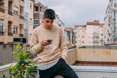 Binanın terasında cep telefonu olan genç bir kız.