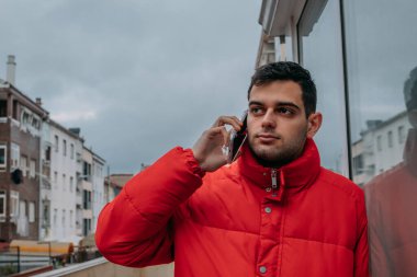 Şehirde cep telefonu ve ceketi olan bir adam var.