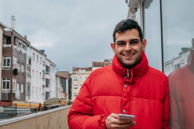 Şehirde cep telefonu ve ceketi olan bir adam var.