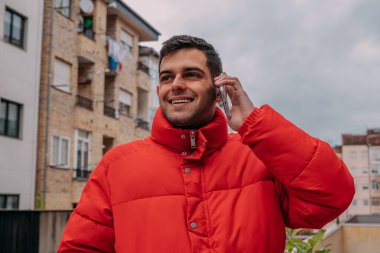 Şehirde cep telefonu ve ceketi olan bir adam var.