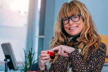 Evde cep telefonuyla kozmetik ürünleri gösteren etken