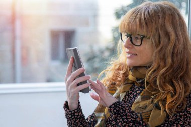 Evde cep telefonu ya da akıllı telefonu olan bir kadın.