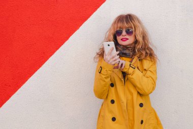 Duvarında kırmızı beyaz bantlı cep telefonu olan bir kadın.