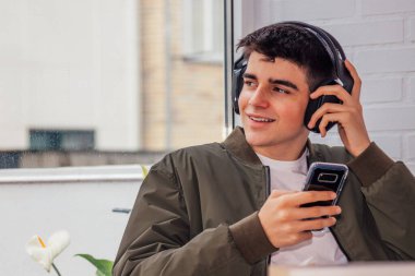 Cep telefonu ve kulaklığı olan genç adam.