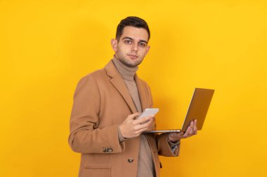 Akıllı telefonu ve dizüstü bilgisayarı olan genç adam arka planda izole edilmiş.