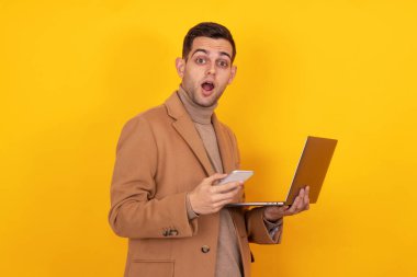 Akıllı telefonu ve dizüstü bilgisayarı olan genç adam arka planda izole edilmiş.