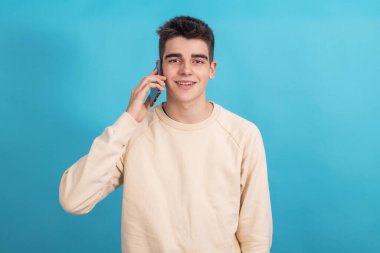 Arka planda cep telefonu olan gülümseyen bir çocuk ya da öğrenci