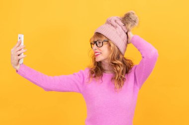 Yetişkin bir kadın arka planda izole edilmiş bir telefonla selfie çekiyor.