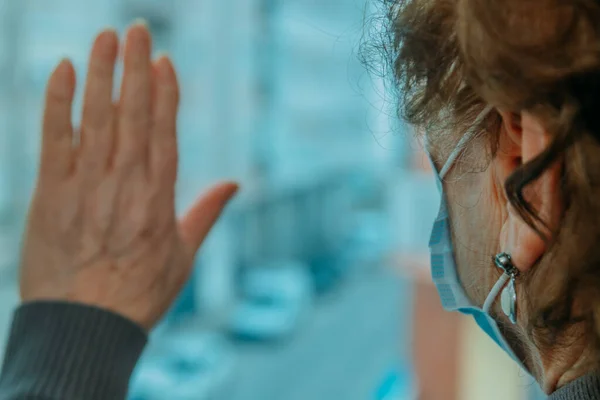 Senioren Vrouw Met Gezichtsmasker Beperkt Thuis Met Hand Raam — Stockfoto
