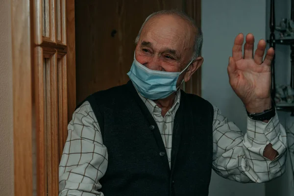 old man or senior with face mask at home at the door