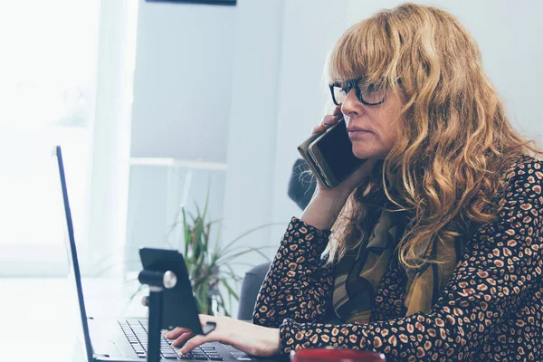 Evde Cep Telefonu Bilgisayarla Çalışan Yetişkin Bir Kadın — Stok fotoğraf